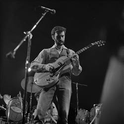 A person playing a guitar on a stage

Description automatically generated
