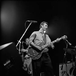A person playing guitar on stage

Description automatically generated