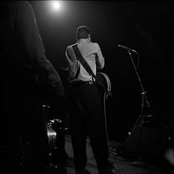 A person playing a guitar on stage

Description automatically generated